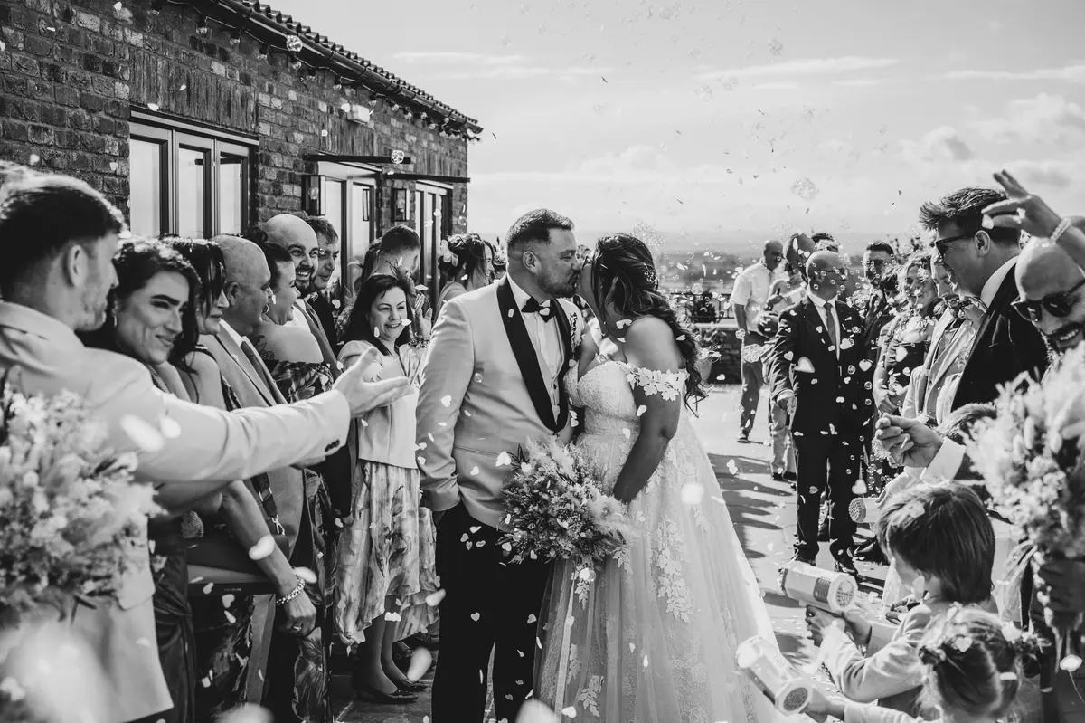 Guests throwing confetti around Star and Dan outside the brick barns