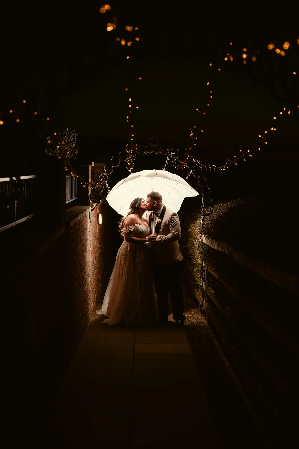 Star and Dan standing beneath the lit courtyard arch after dark