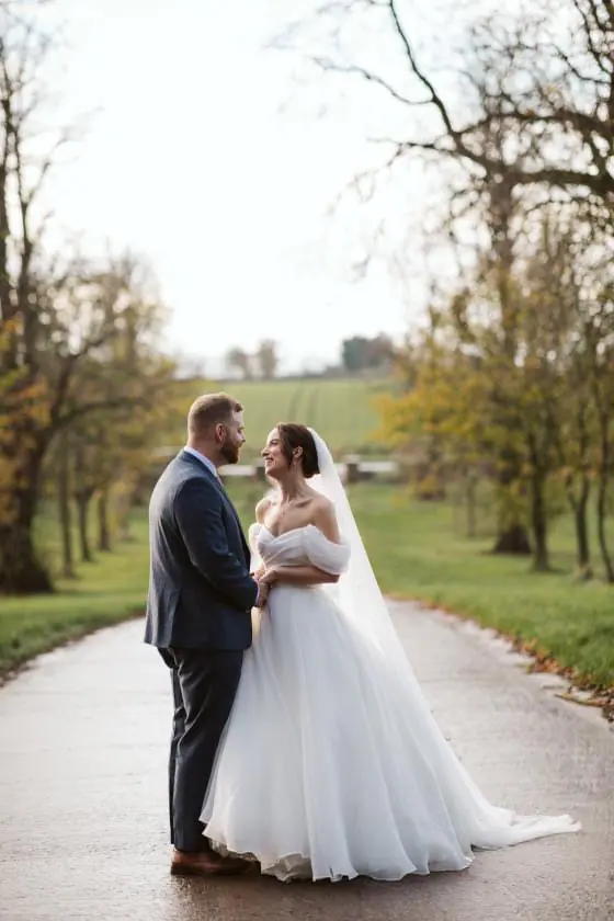 Zoe and Scott facing each other on the tree-lined approach