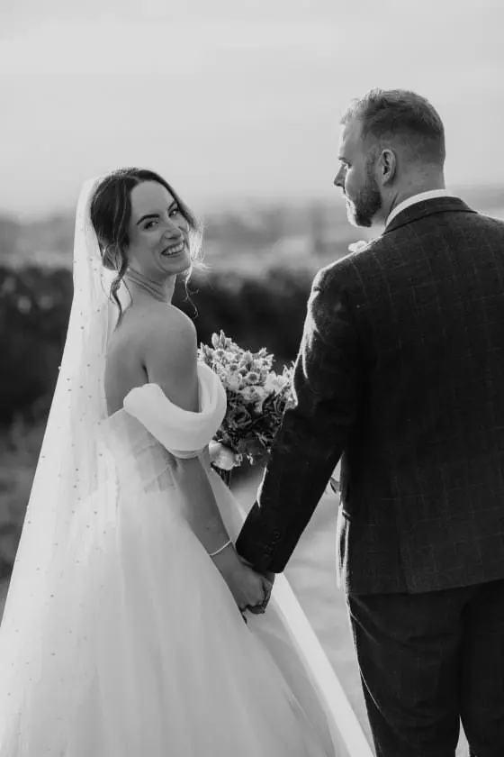 Zoe looking back while holding Scott's hand in black and white