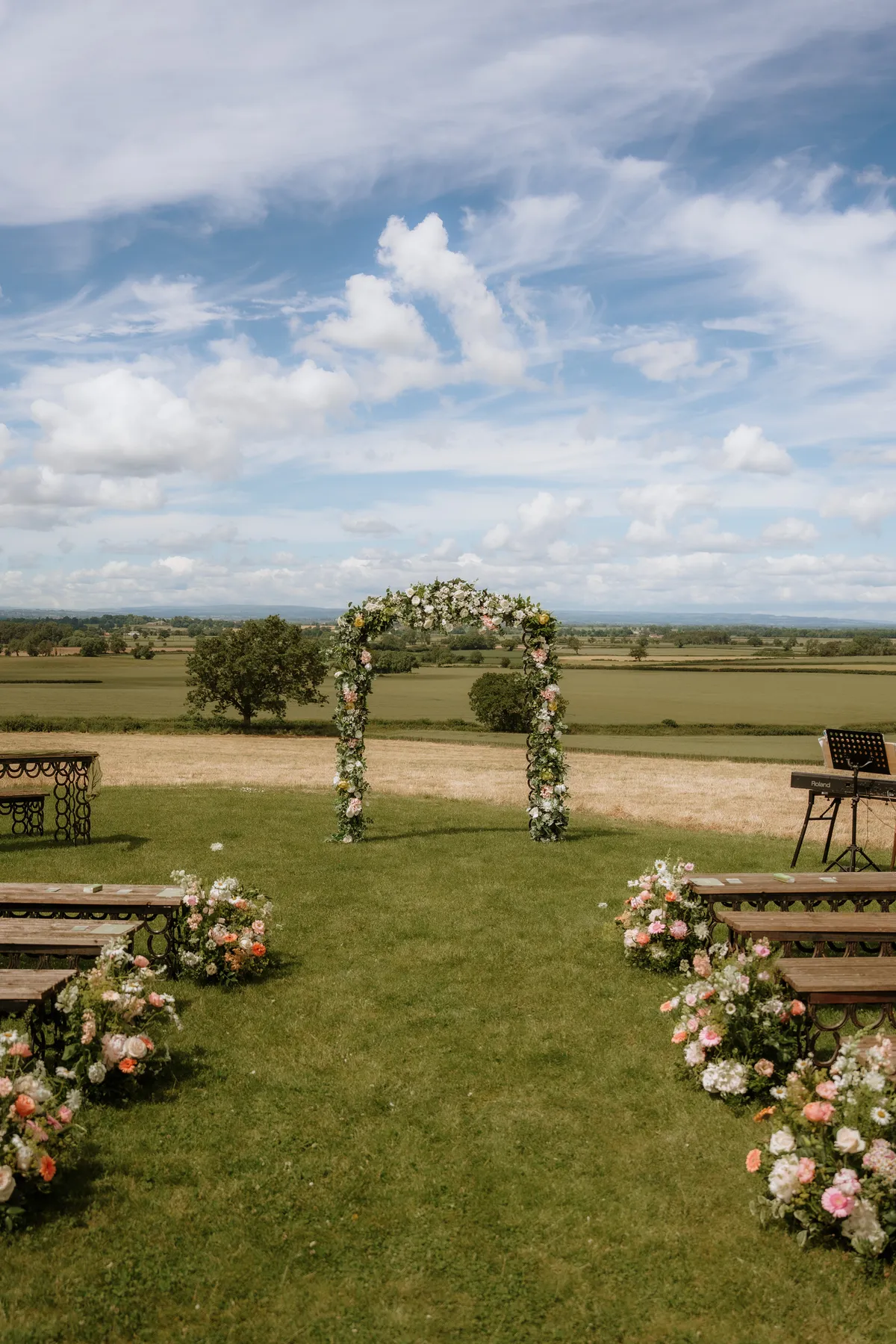 A flower-filled outdoor ceremony arch and aisle overlooking the North Yorkshire countryside at Thief Hall