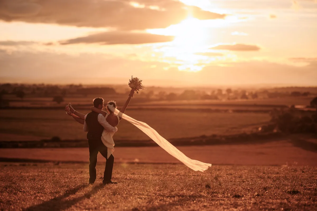 A couple embracing in a field at sunset
