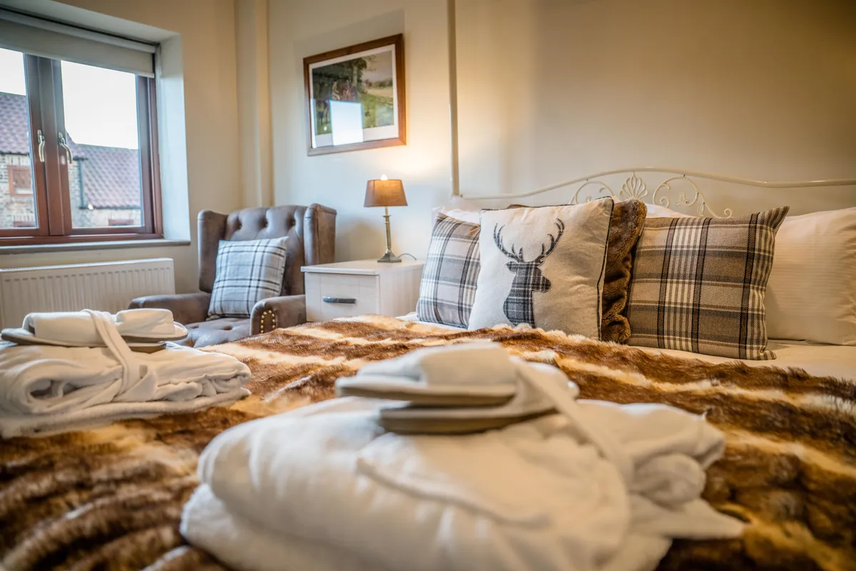 Bedroom with a pale metal bed and stag cushion in Turpin Cottage
