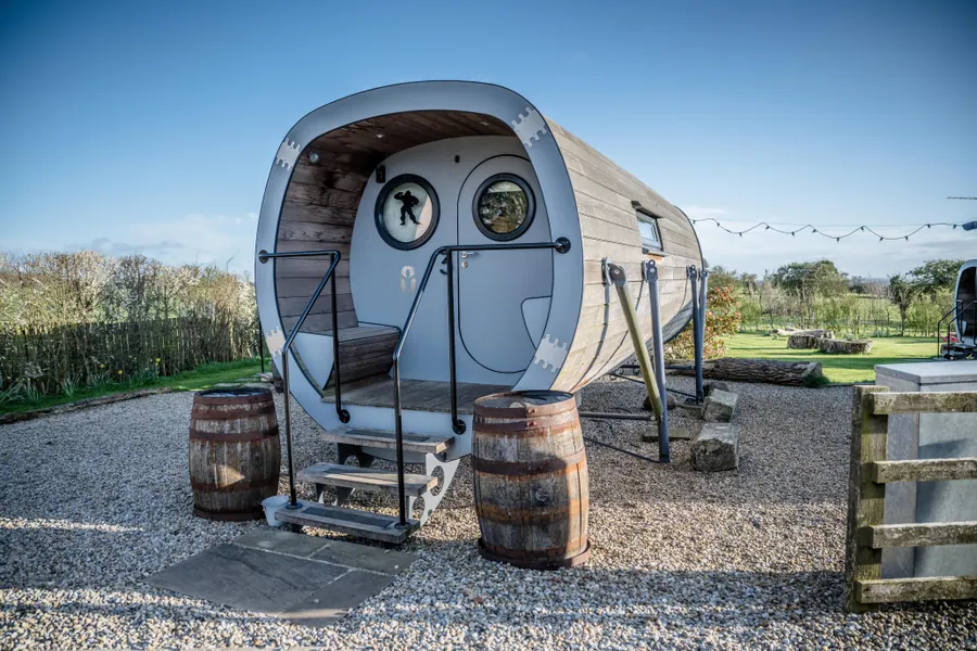 A timber-clad pod with a curved front and barrel tables outside