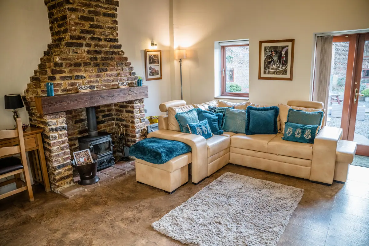 A cottage living room with a brick fireplace and log burner