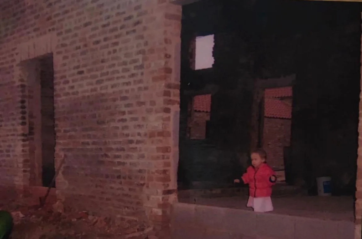 A child standing inside the brick barns while construction work was underway
