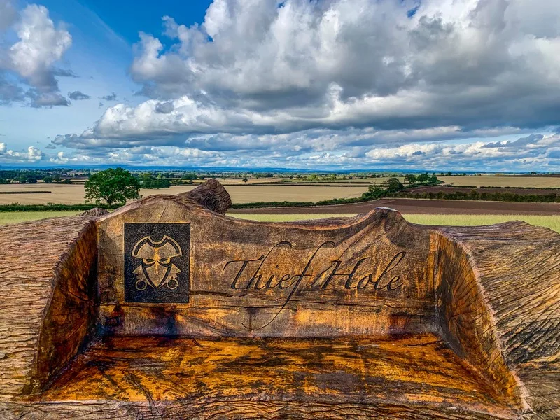 Carved wooden Thief Hole bench overlooking the countryside at Thief Hall